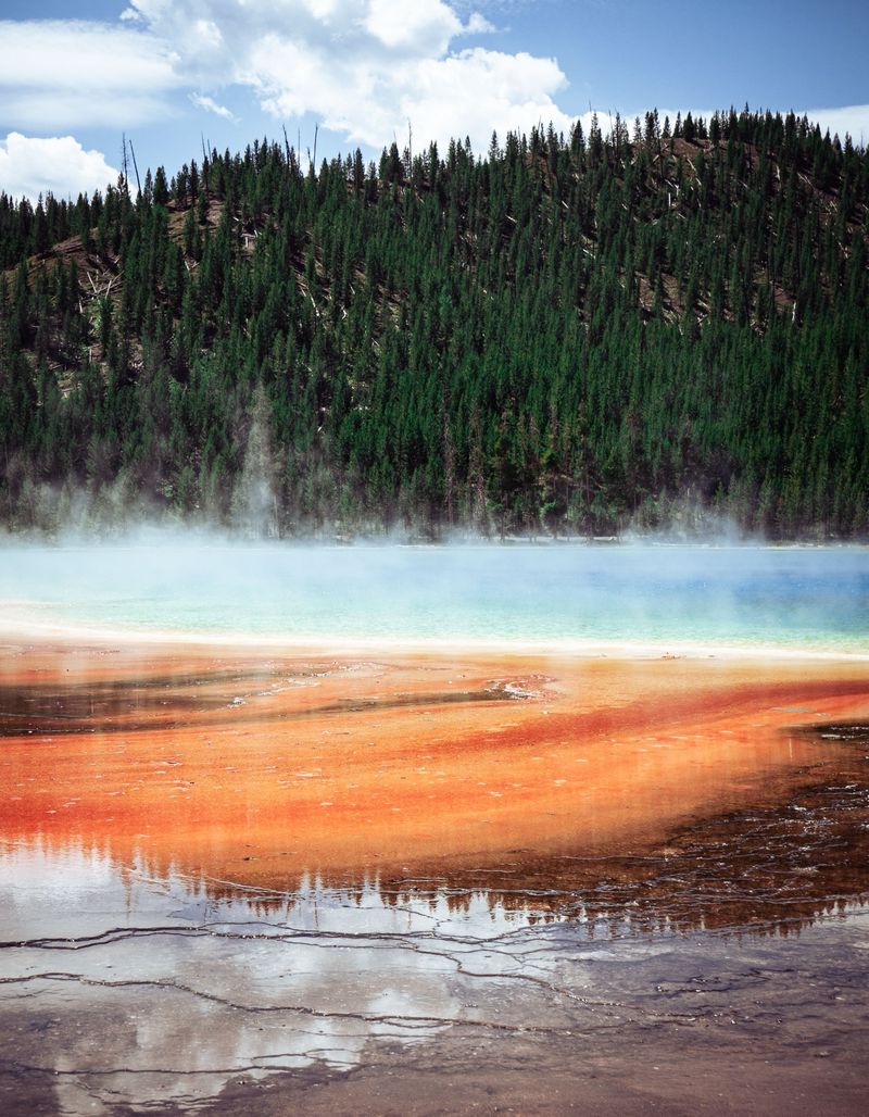 Steam rising over the orange and turquoise colours of a Yellowstone hot spring